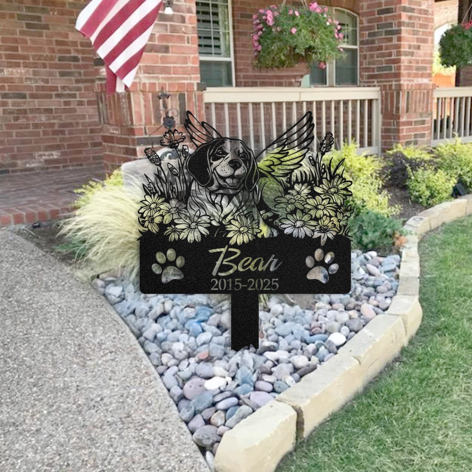 Beagle pet grave marker placed in a rock garden bed in front of a brick house porch with an American flag
