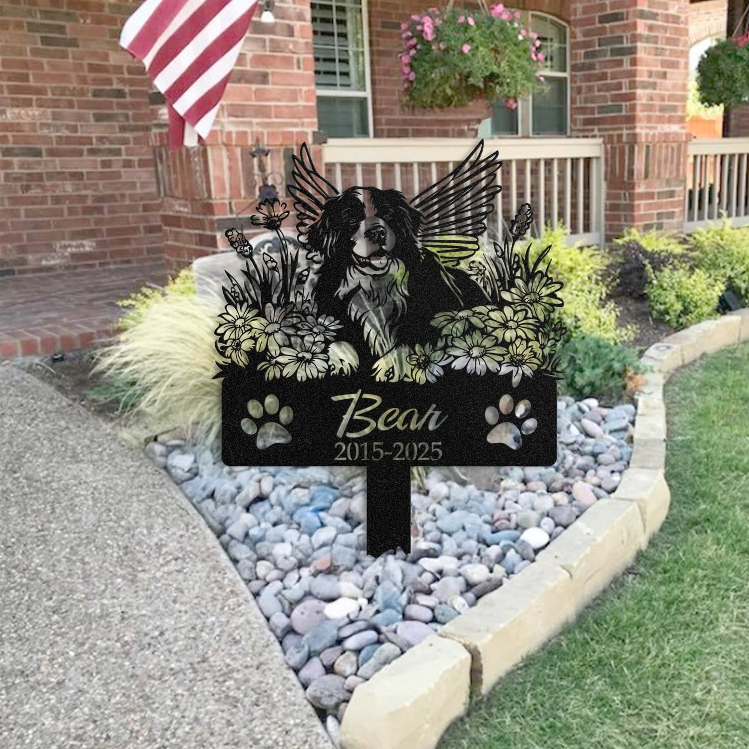 Bernese Mountain Dog pet grave marker placed in a rock garden bed in front of a brick house porch with an American flag