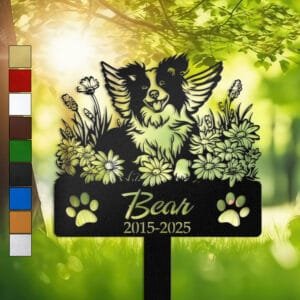 Personalized Border Collie metal pet grave marker with angel wings and daisy flowers, displayed in a sunlit garden with color swatch options