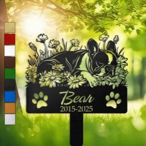 Personalized Boston Terrier metal pet grave marker in a sleeping pose surrounded by daisy flowers, displayed in a sunlit garden with color swatch options
