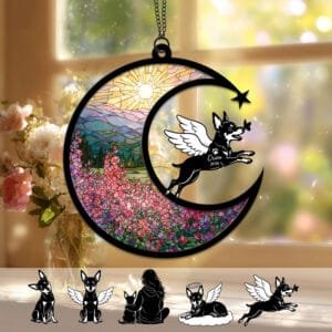 Crescent moon suncatcher with a playful angel-winged Miniature Pinscher silhouette leaping toward a butterfly over a stained-glass wildflower field