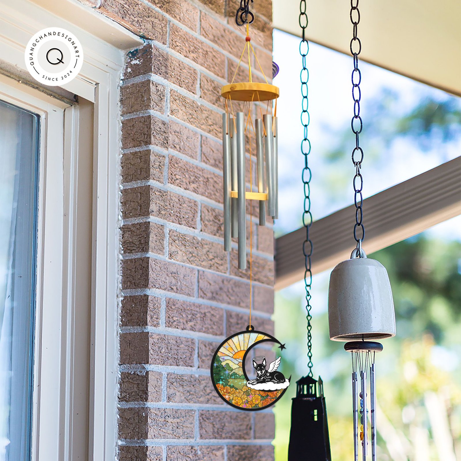 Wind chime with a Miniature Pinscher memorial suncatcher hanging outdoors near a brick wall alongside other garden bells and chimes