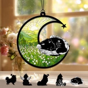 Crescent moon suncatcher with a sleeping angel-winged Pomeranian silhouette curled on the moon above a stained-glass lily of the valley field