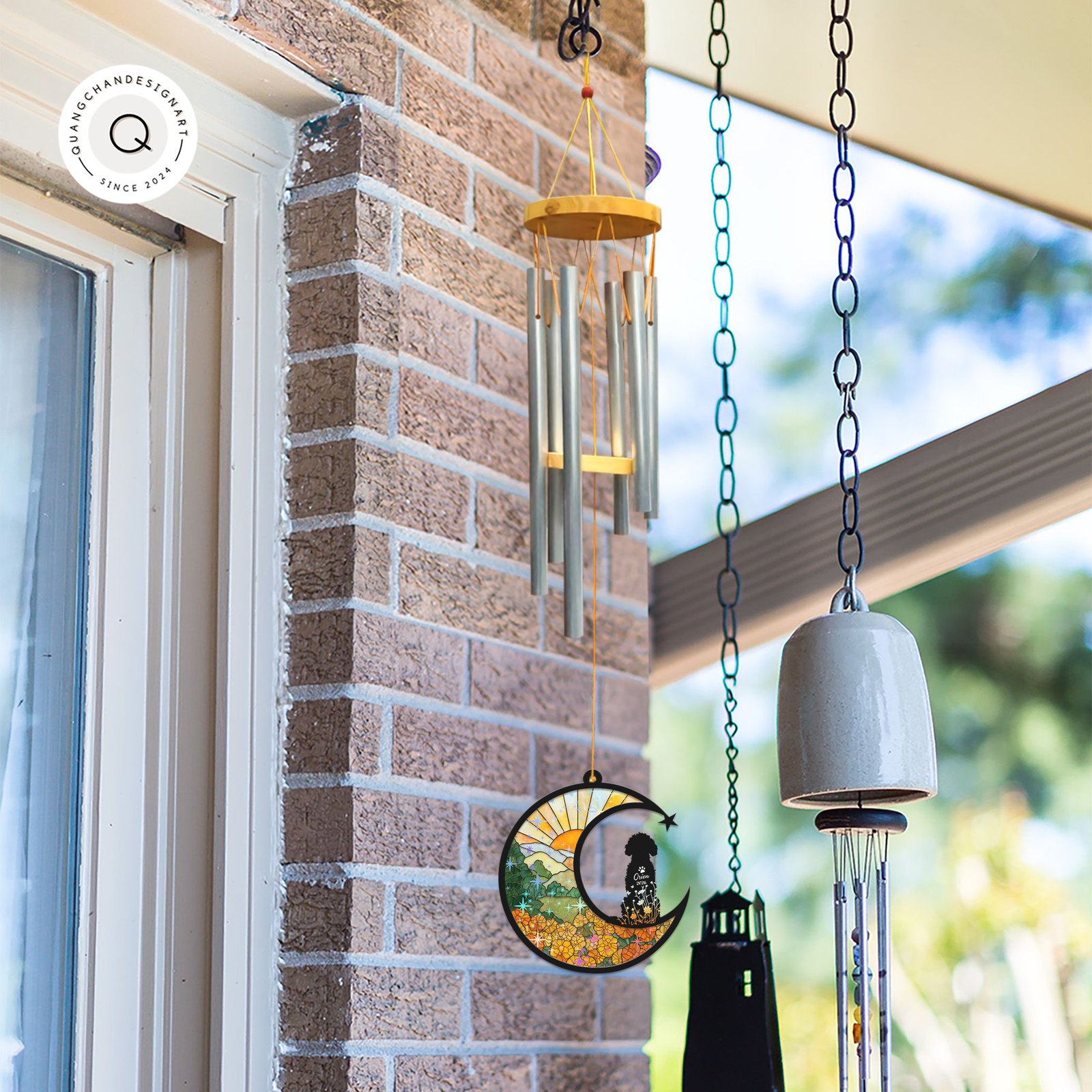 Wind chime with a Poodle memorial suncatcher hanging outdoors near a brick wall alongside other garden bells and chimes