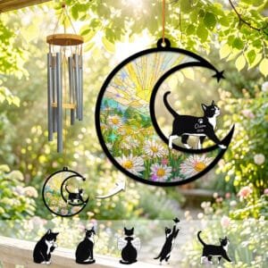 Black and white Tuxedo cat silhouette walking across a stained-glass crescent moon wind chime suncatcher over a daisy field