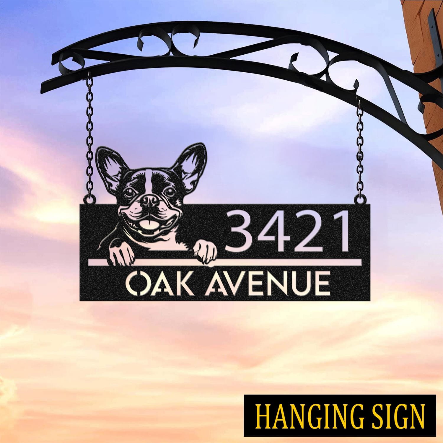 Boston Terrier address sign hanging by chains from a wrought iron bracket against a sunset sky