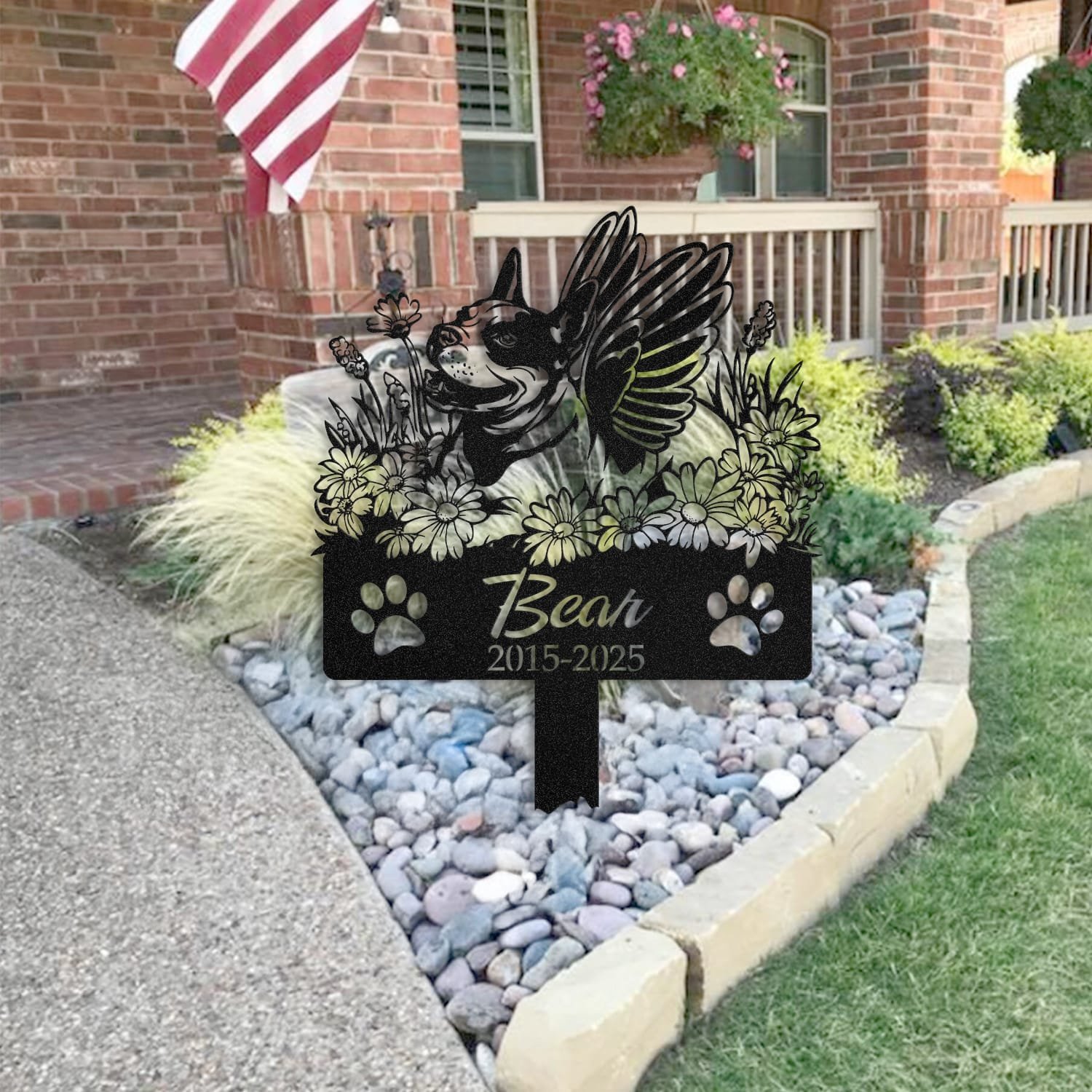 Bull Terrier pet grave marker placed in a rock garden bed in front of a brick house porch with an American flag