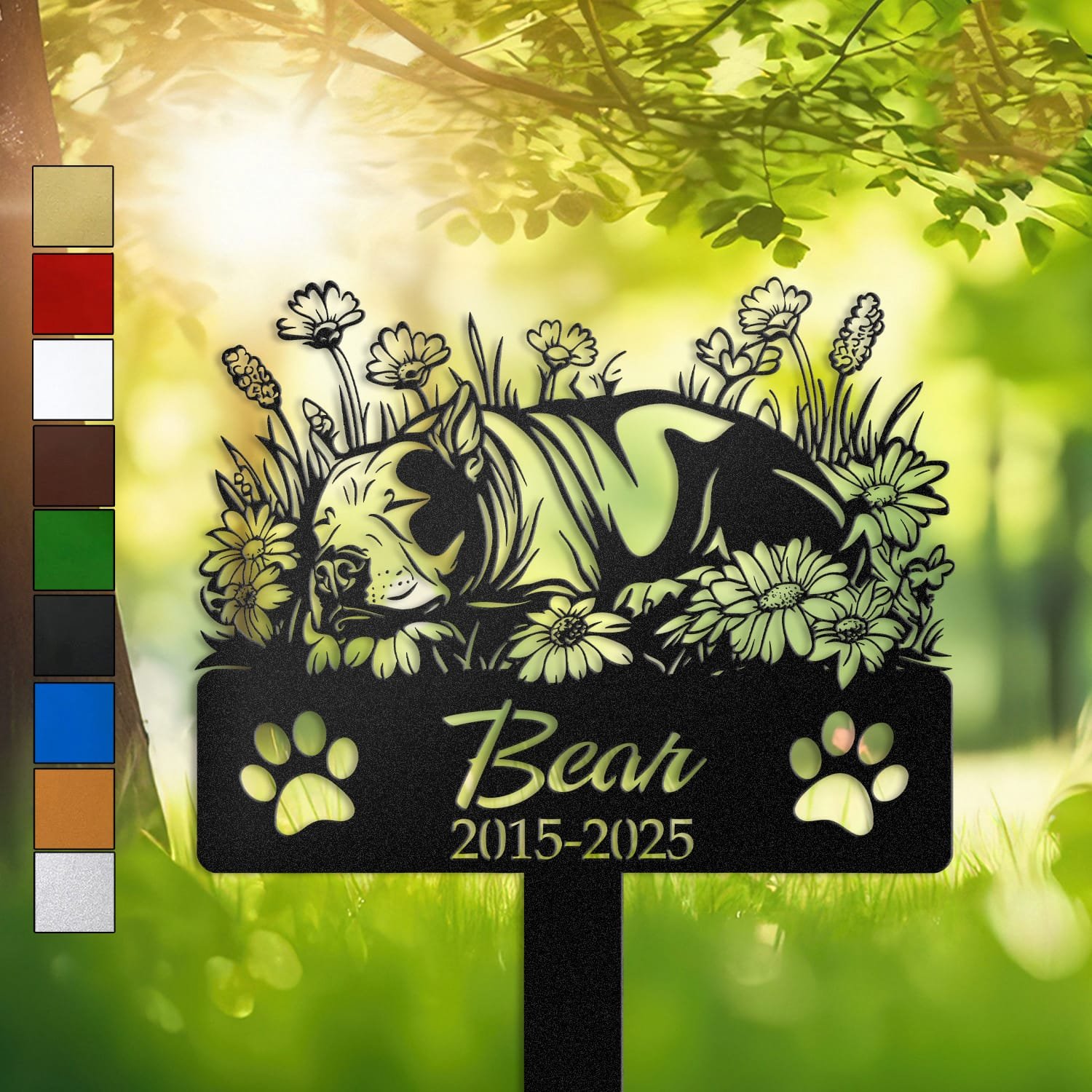 Personalized Bull Terrier metal pet grave marker in a sleeping pose surrounded by daisy flowers, displayed in a sunlit garden with color swatch options