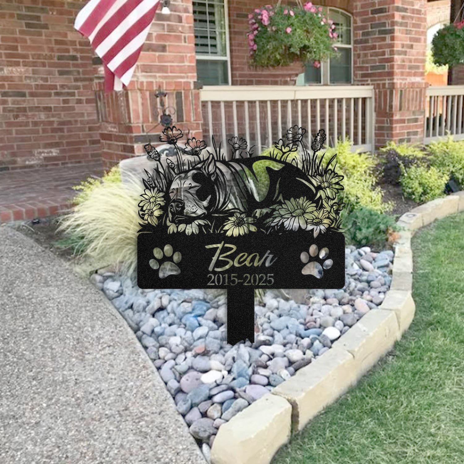 Bull Terrier pet grave marker placed in a rock garden bed in front of a brick house porch with an American flag