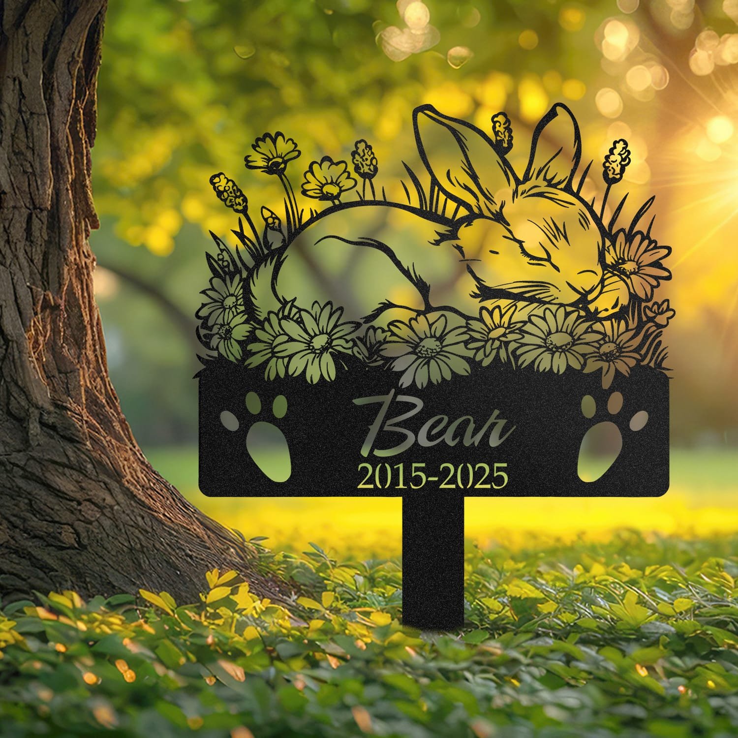 Bunny pet grave marker displayed outdoors in a garden setting, showing the personalized sleeping-pose daisy floral design in place on the stake.