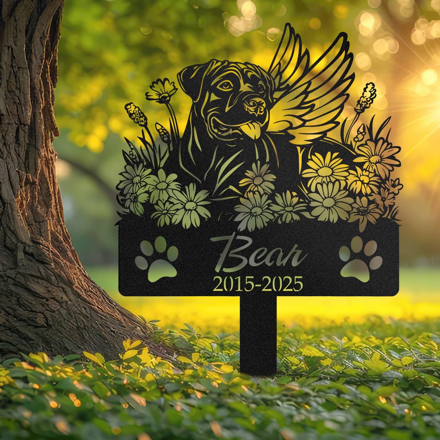 Cane Corso angel wings pet grave marker staked into the ground beside a large tree trunk in a garden setting