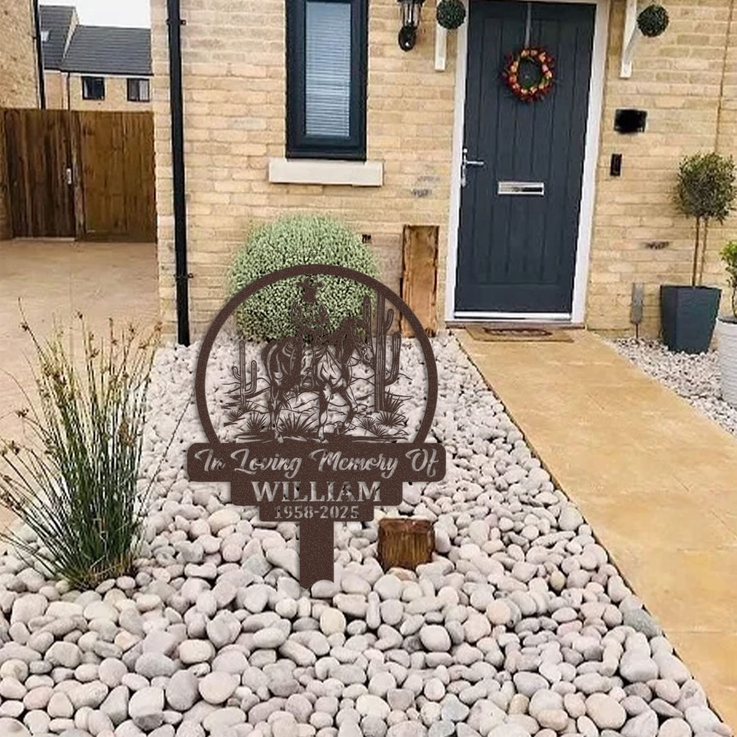 Cowboy human grave marker displayed among garden plants and stone edging, showing the design as an outdoor memorial accent.