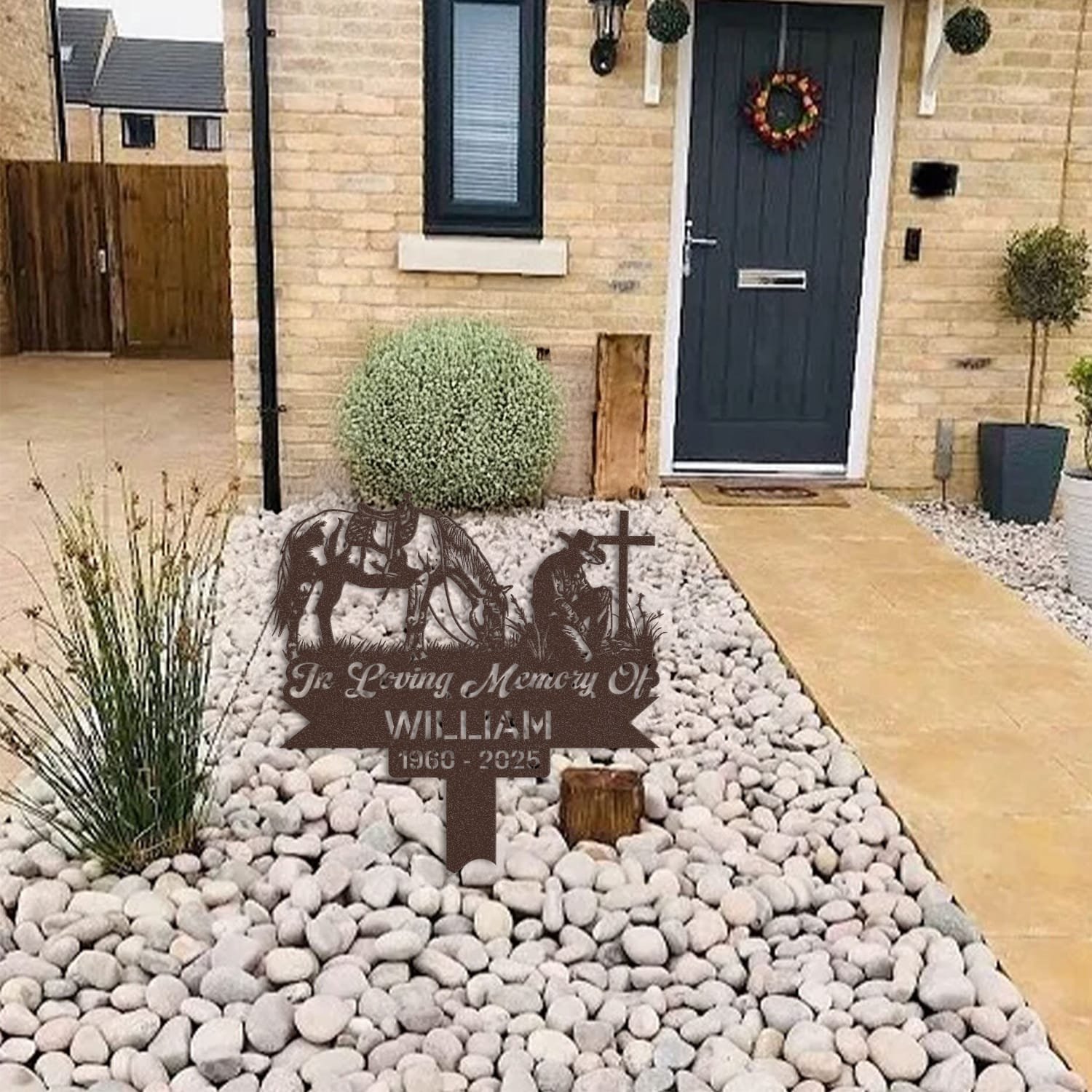Cowboy human grave marker displayed among garden plants and stone edging, showing the design as an outdoor memorial accent.