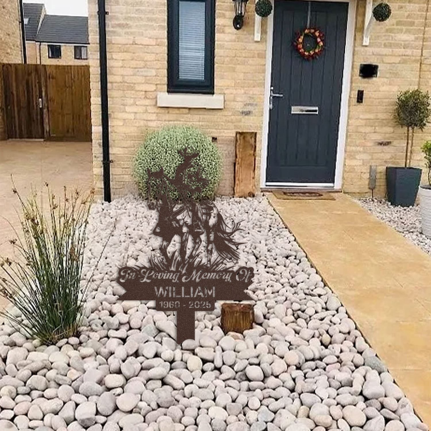 Cowboy human grave marker displayed among garden plants and stone edging, showing the design as an outdoor memorial accent.