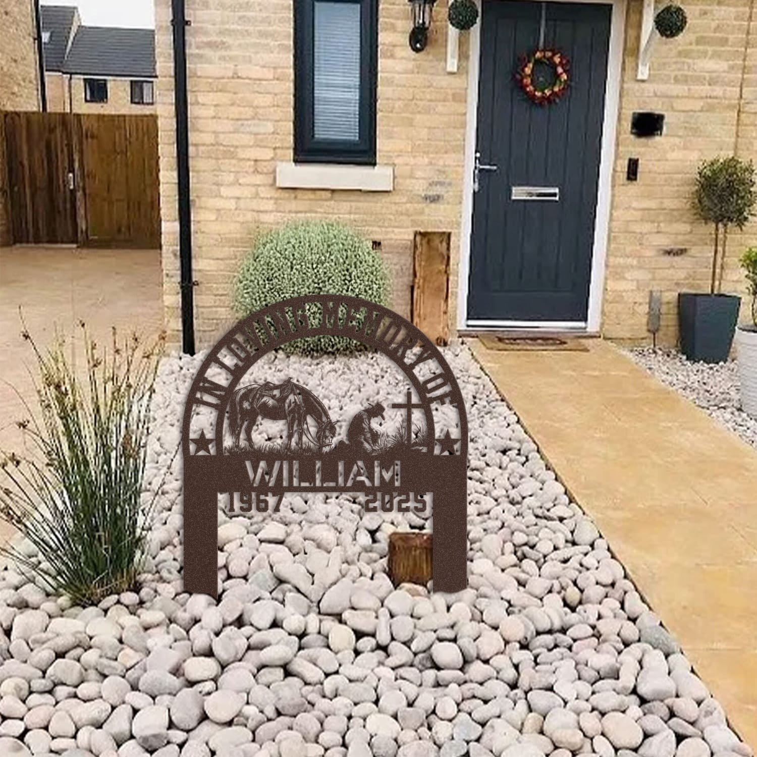 Cowboy human grave marker displayed among garden plants and stone edging, showing the design as an outdoor memorial accent.