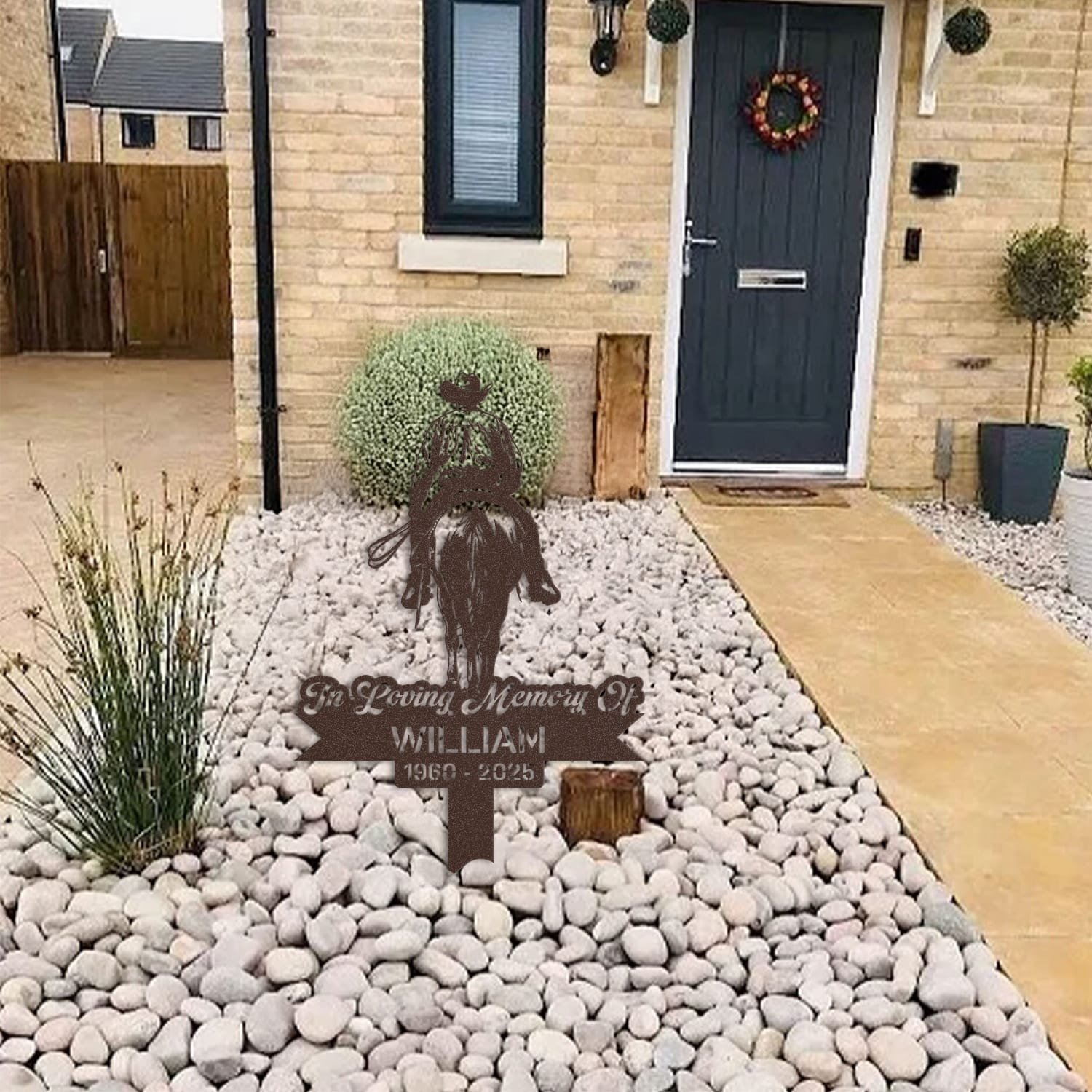 Cowboy human grave marker displayed among garden plants and stone edging, showing the design as an outdoor memorial accent.