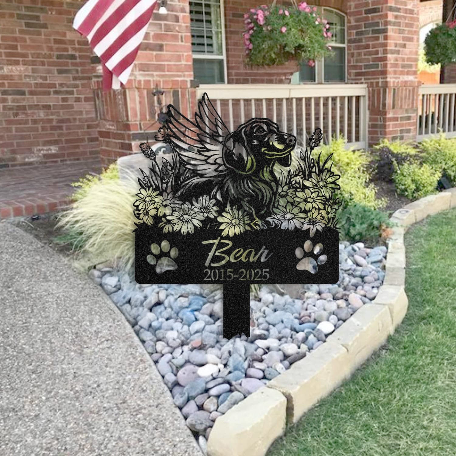 Dachshund pet grave marker staged near a home entryway, showing the finished angel wings and daisy floral design and name plate outdoors.