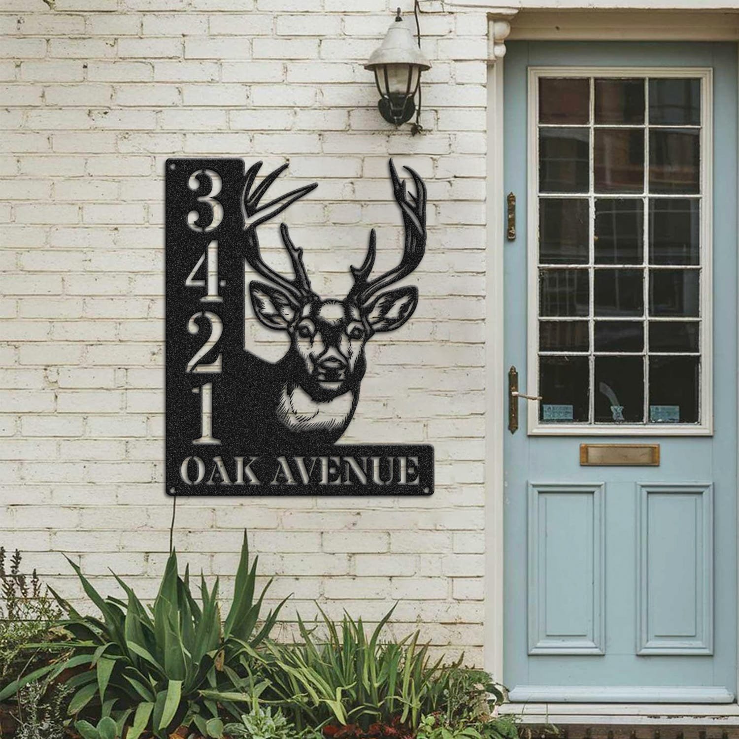Deer address sign mounted on a painted brick wall beside a wooden front door
