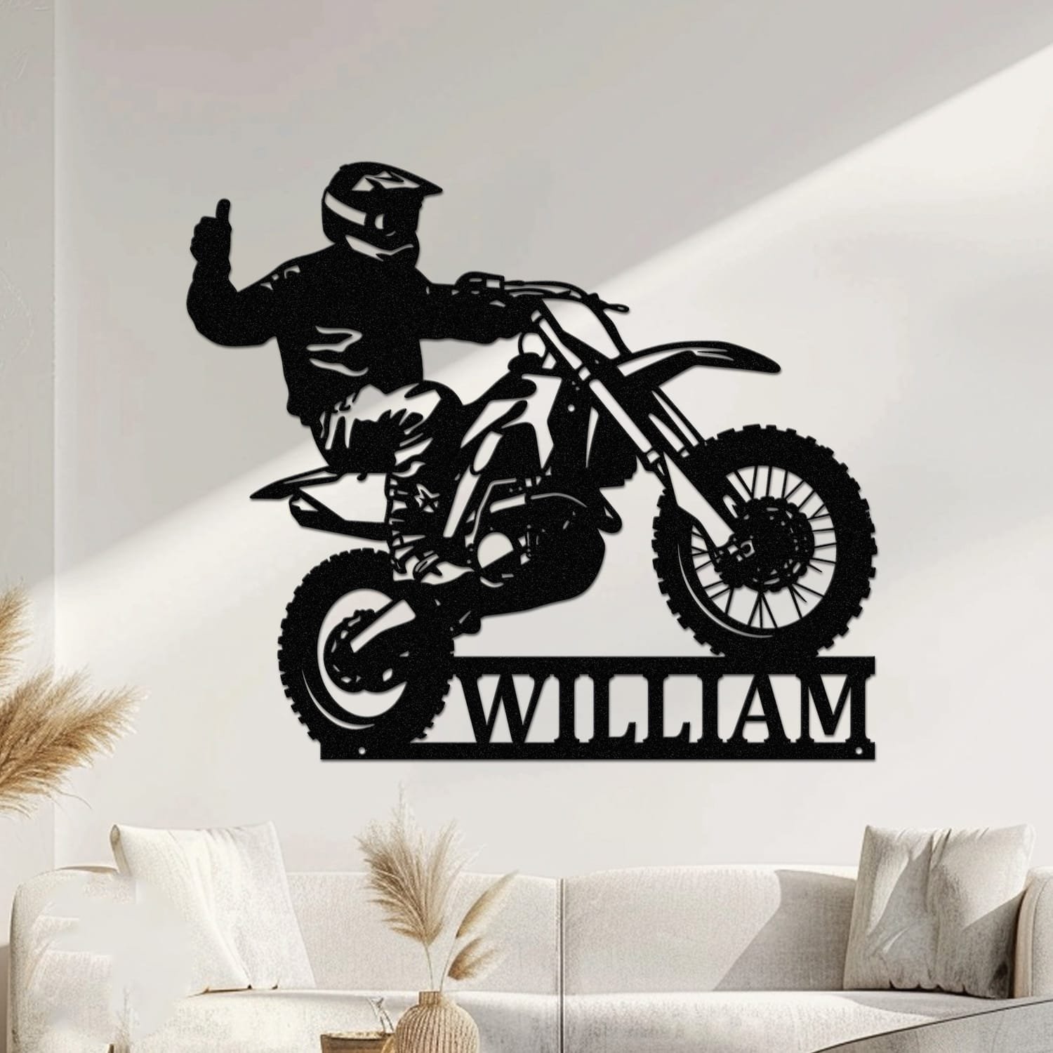 Rider giving a thumbs-up while catching air on a motocross dirt bike, with a custom name cut into the base of a personalized metal wall sign.