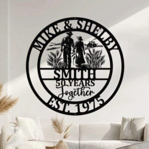 Metal wall art design of a farmer couple walking hand in hand away from the viewer through a field, with a tractor in the background, set within a circular frame reading the couple's names at the top and their last name, years together, and established year at the bottom, fully personalizable.