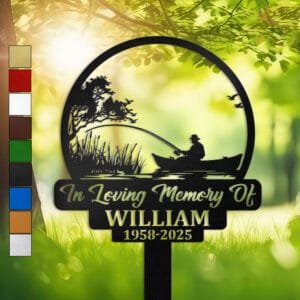 Metal memorial design of a fisherman fishing from a boat beneath a tree with birds taking flight, set within a circular medallion frame and engraved with 'In Loving Memory Of', personalized with a name and memorial years.