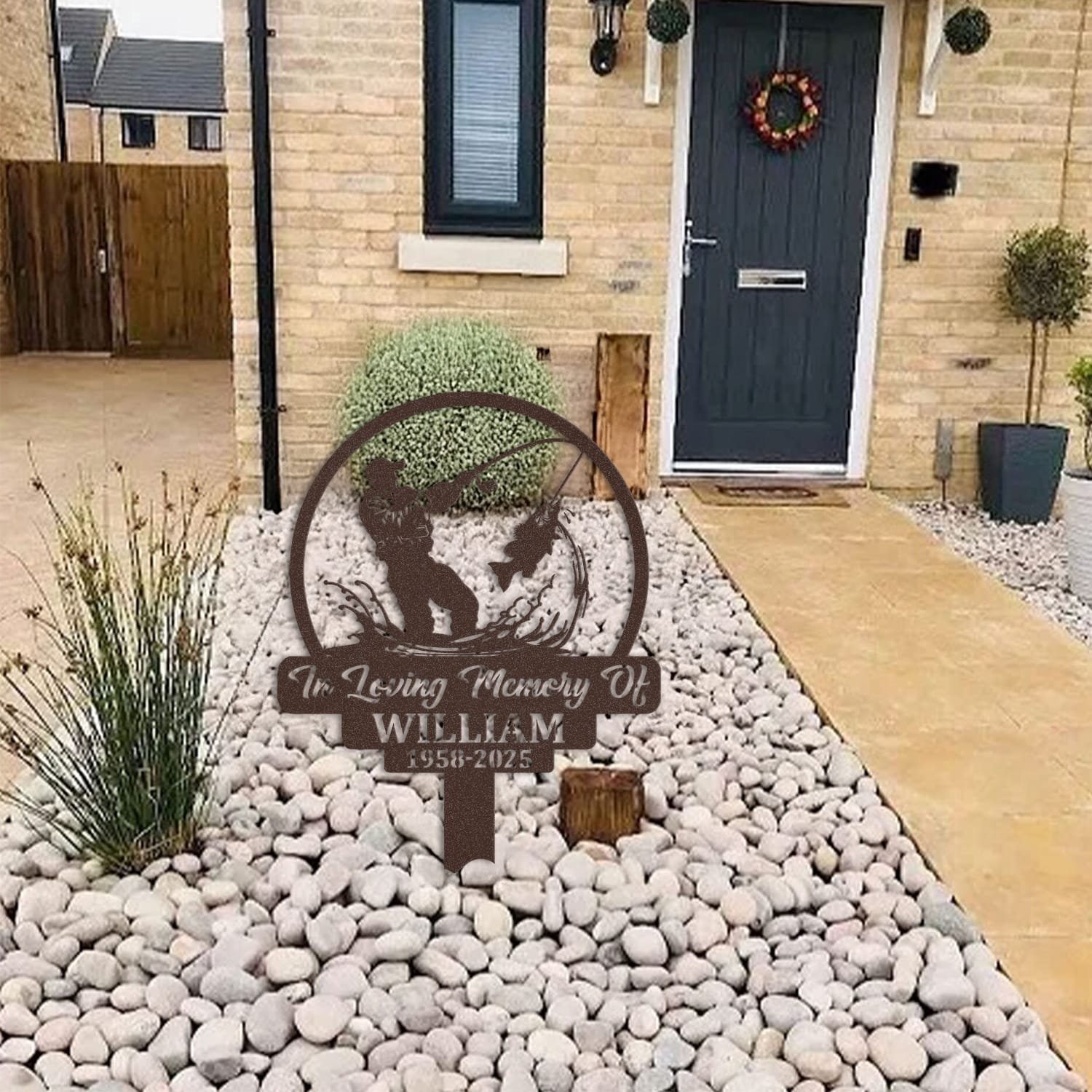 Fisherman human grave marker displayed among garden plants and stone edging, showing the design as an outdoor memorial accent.