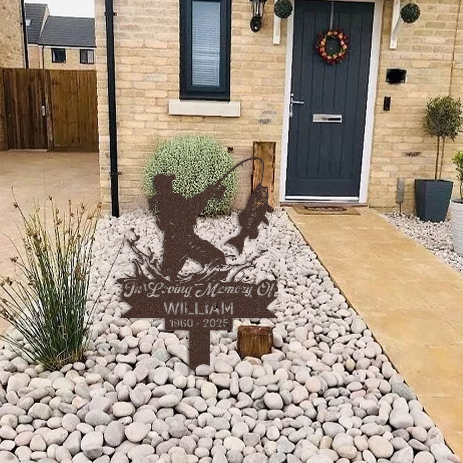 Fisherman human grave marker displayed among garden plants and stone edging, showing the design as an outdoor memorial accent.