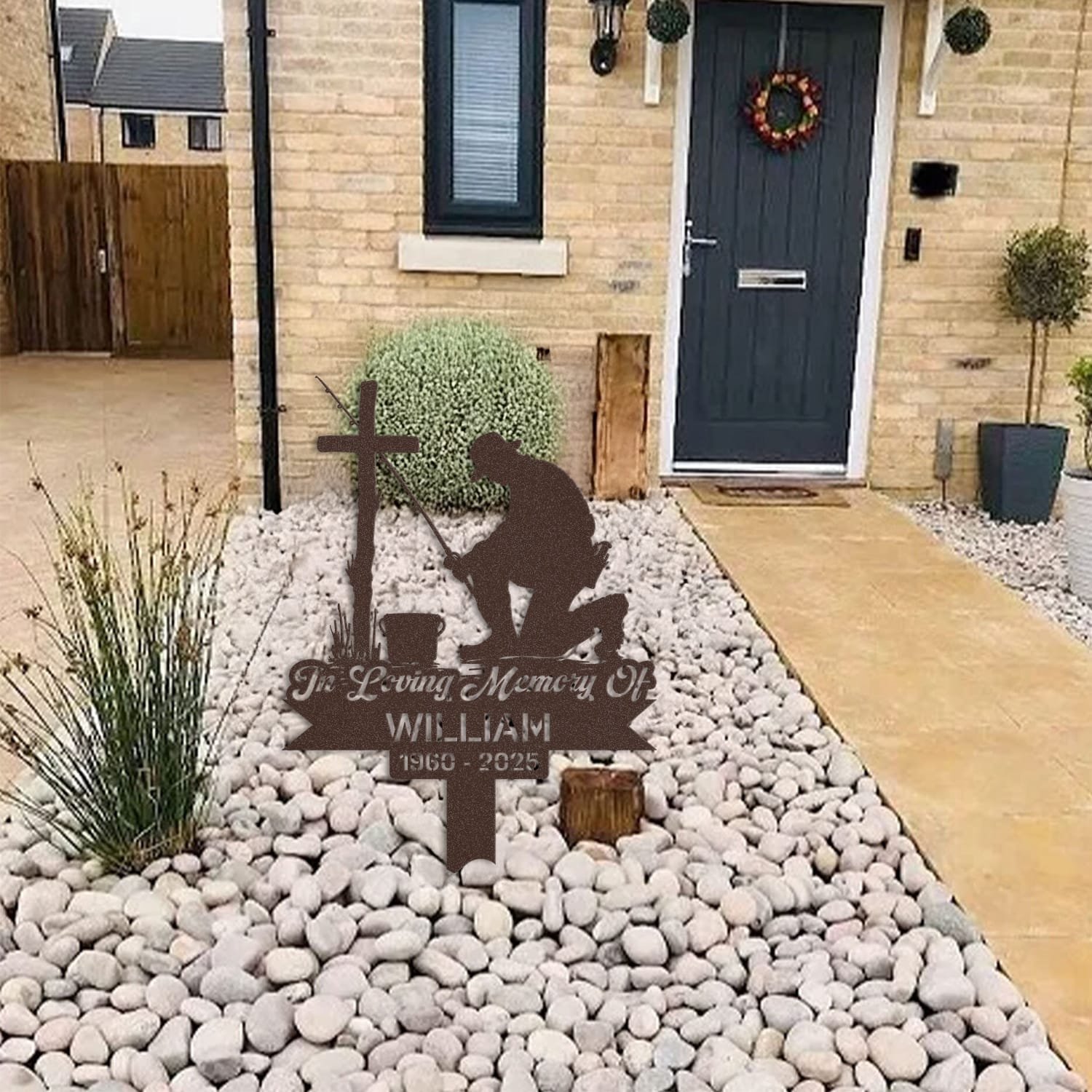 Fisherman human grave marker displayed among garden plants and stone edging, showing the design as an outdoor memorial accent.