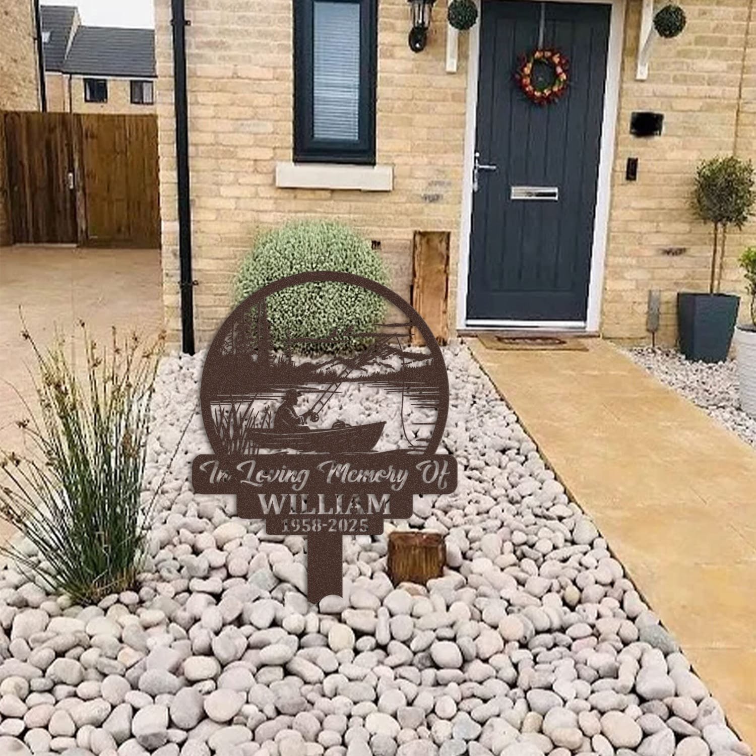 Fisherman human grave marker displayed among garden plants and stone edging, showing the design as an outdoor memorial accent.