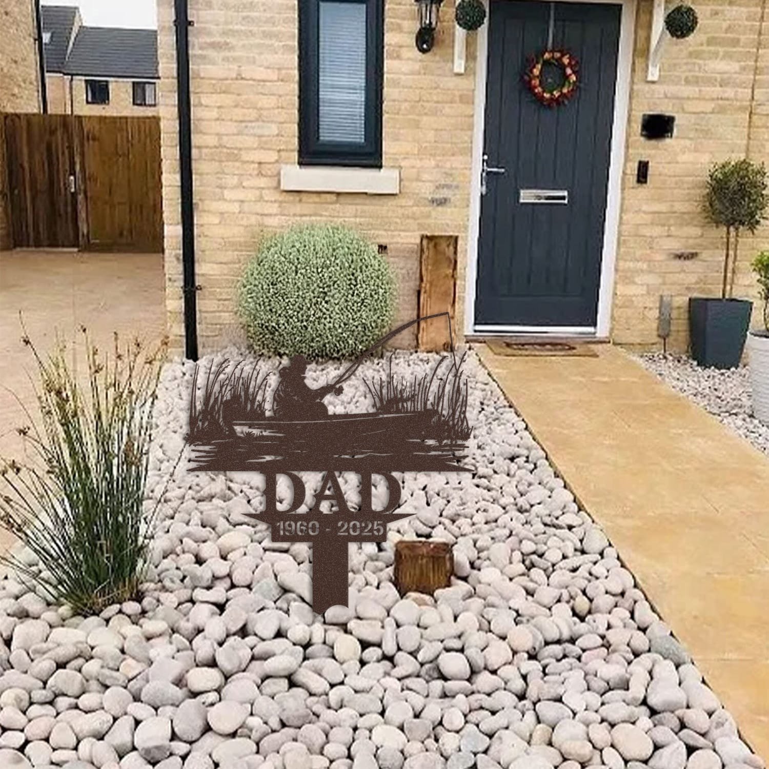 Fisherman human grave marker displayed among garden plants and stone edging, showing the design as an outdoor memorial accent.