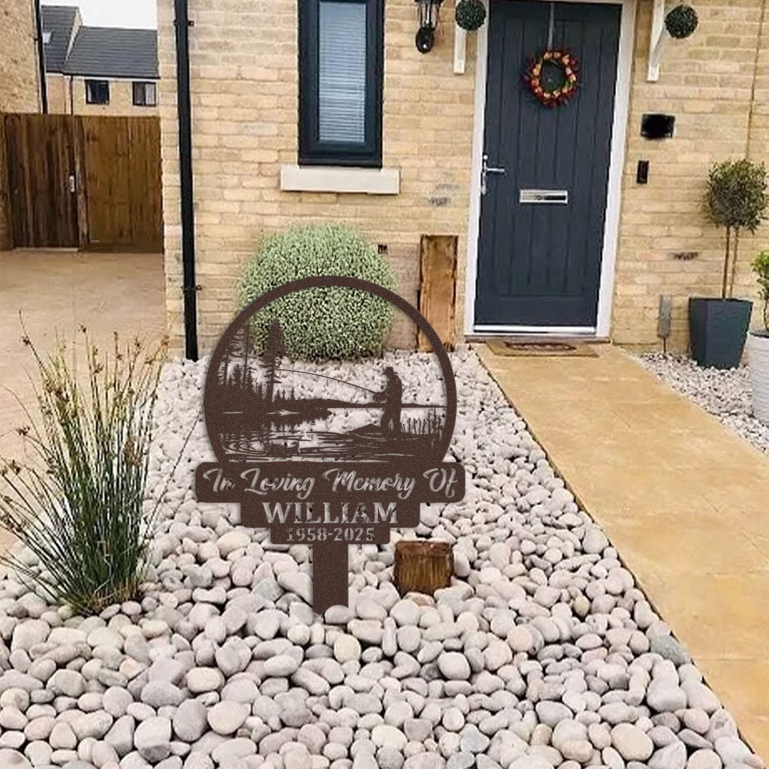 Fisherman human grave marker displayed among garden plants and stone edging, showing the design as an outdoor memorial accent.