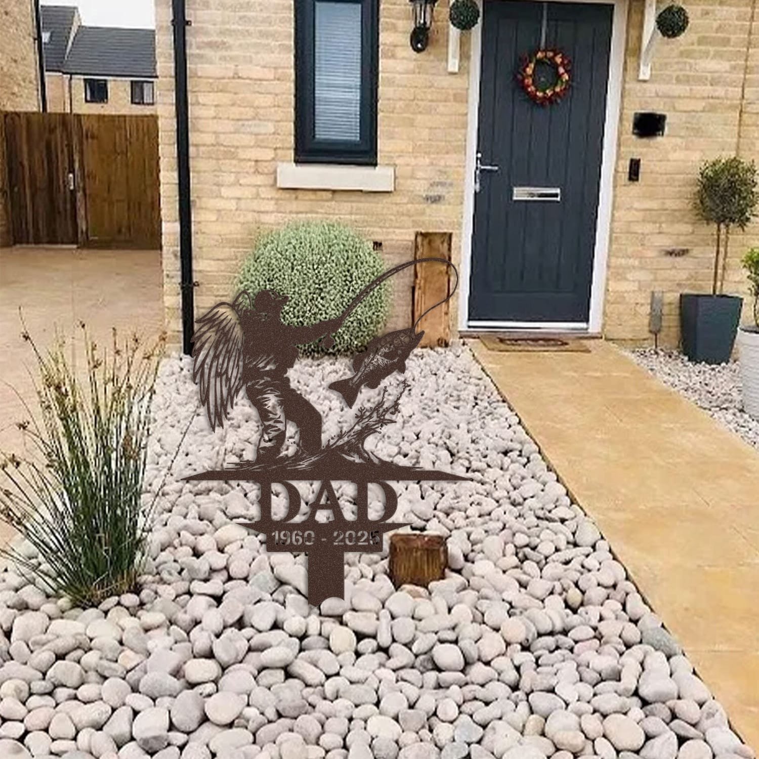 Fisherman human grave marker displayed among garden plants and stone edging, showing the design as an outdoor memorial accent.