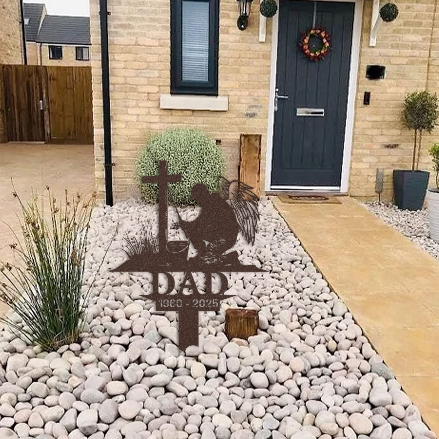 Fisherman human grave marker displayed among garden plants and stone edging, showing the design as an outdoor memorial accent.