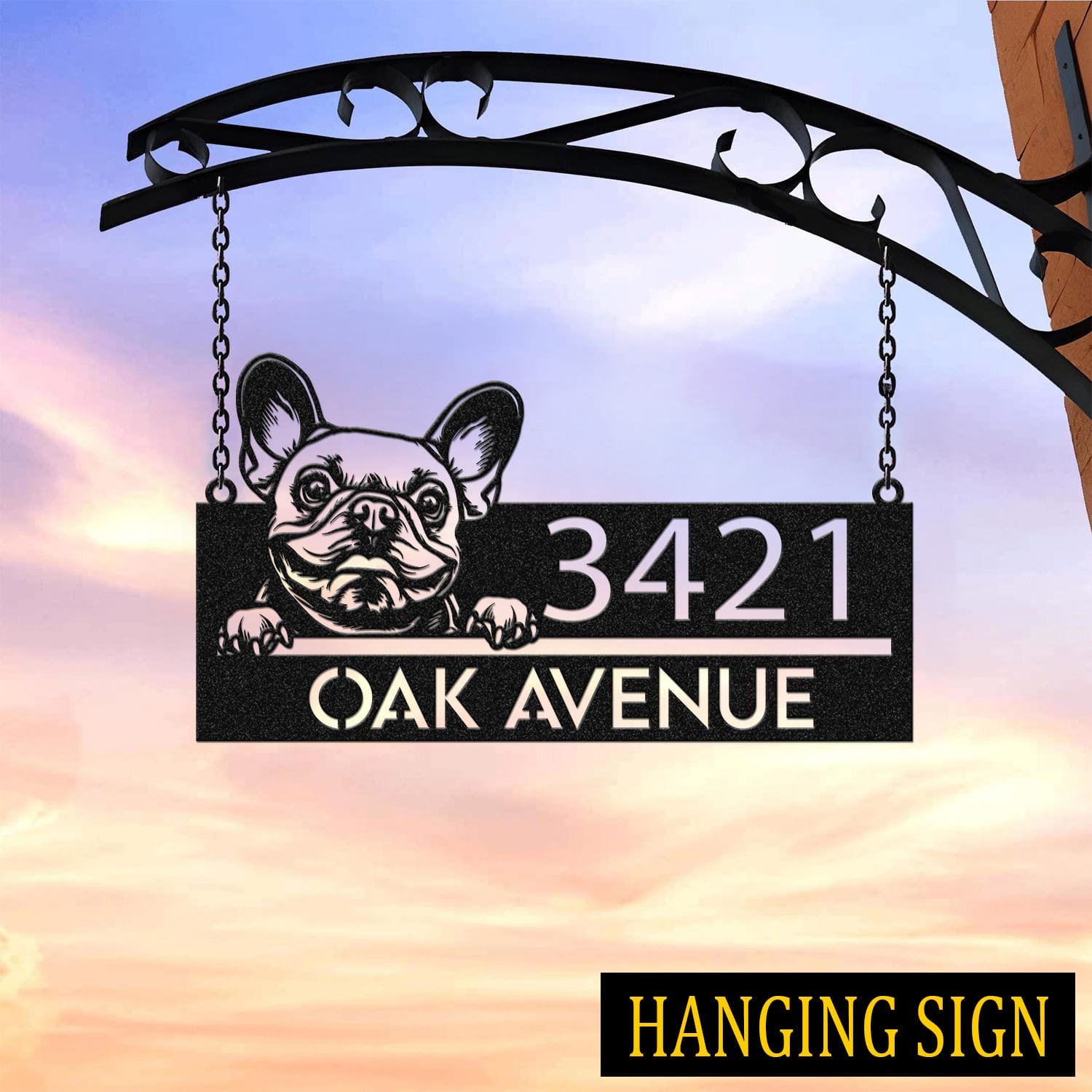 French Bulldog address sign hanging by chains from a wrought iron bracket against a sunset sky