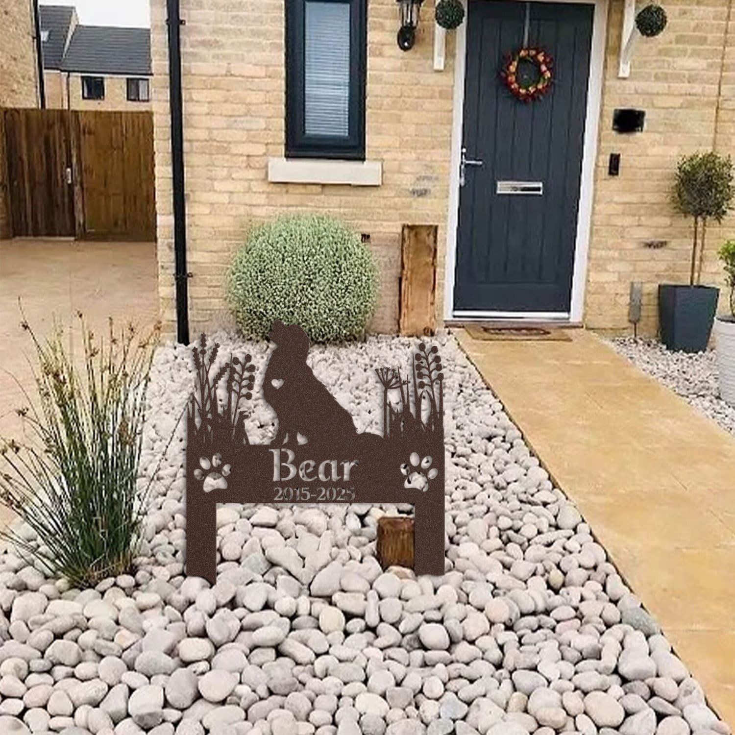 Golden Retriever pet grave marker displayed among garden plants and stone edging, showing the heart-cutout silhouette design as an outdoor memorial accent.