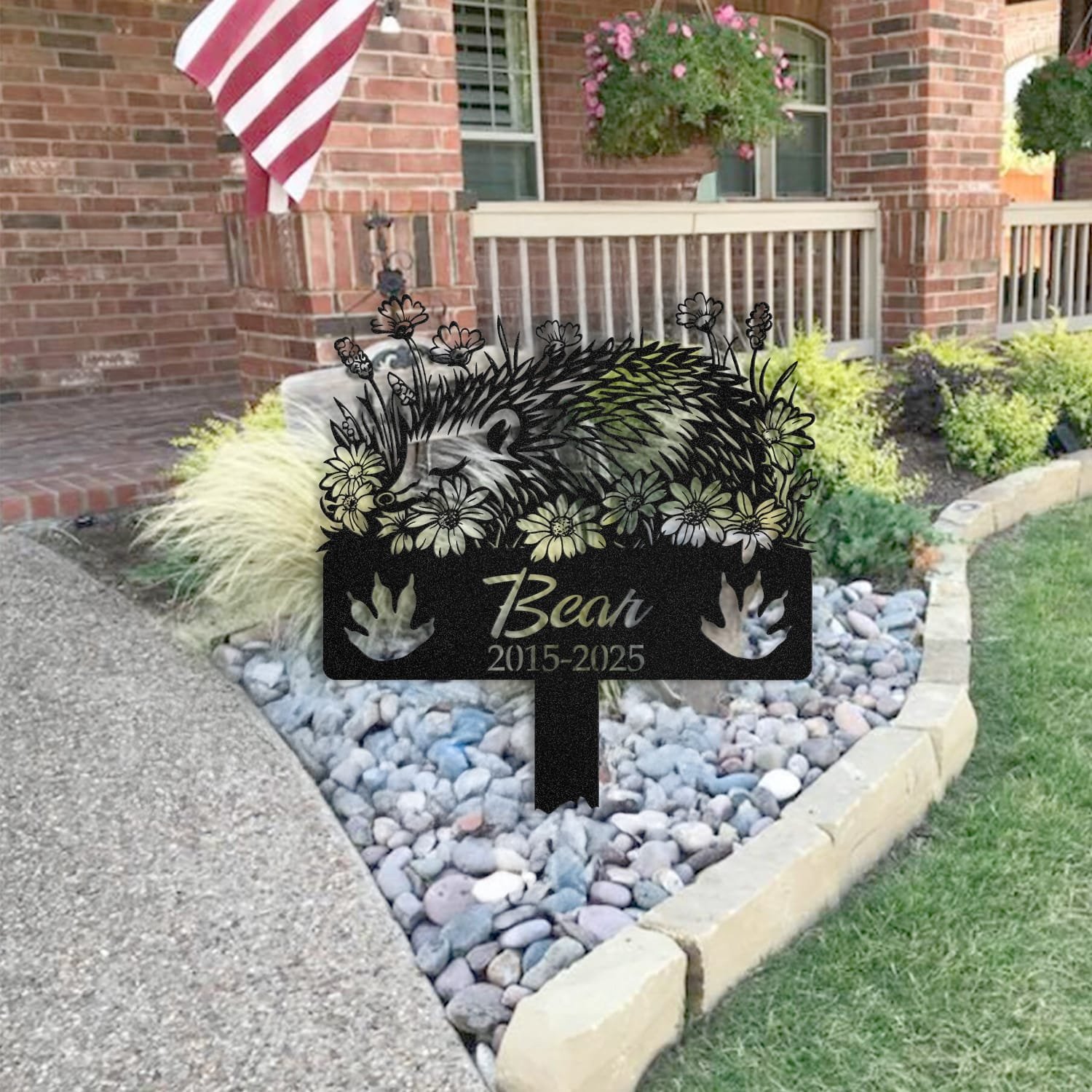 Hedgehog pet grave marker staged near a home entryway, showing the finished sleeping-pose daisy floral design and name plate outdoors.
