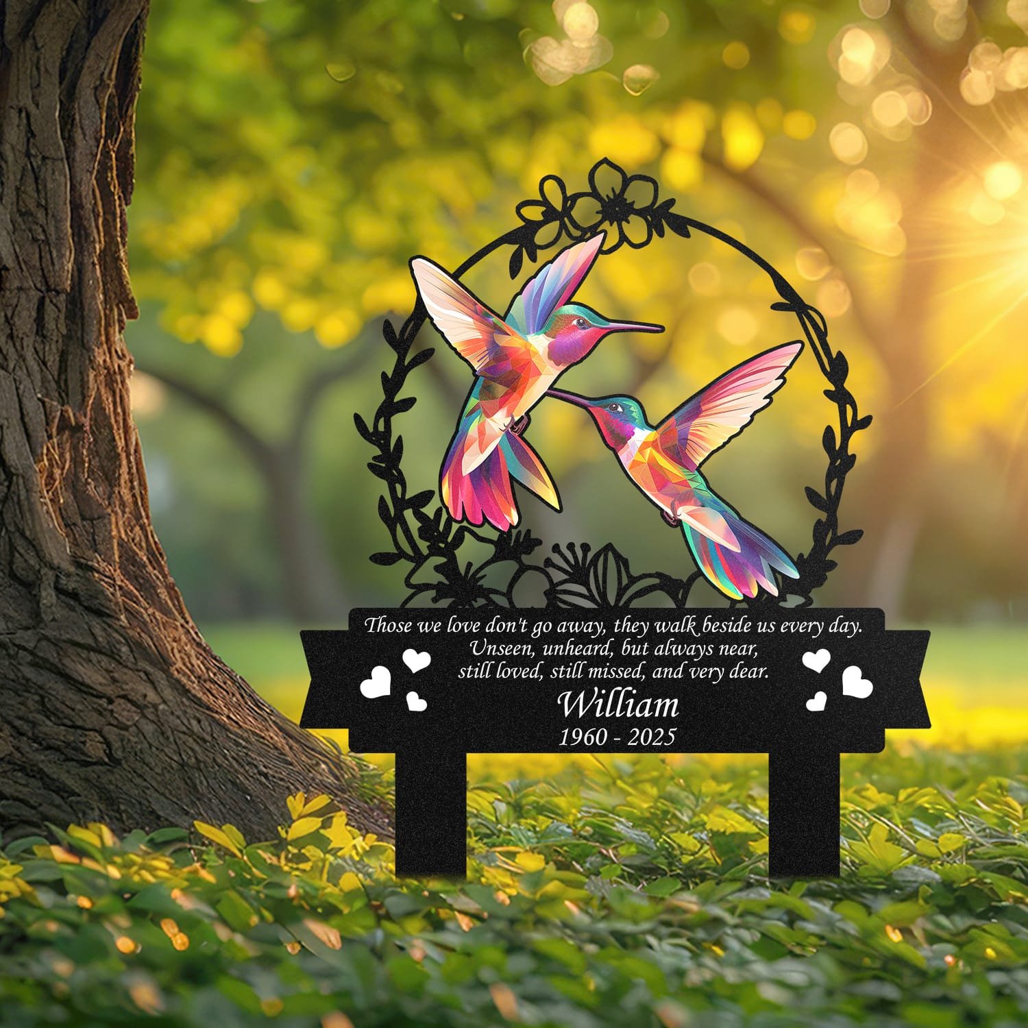 Hummingbird human grave marker displayed outdoors in a garden setting, showing the personalized floral wreath bird-pair design in place on the stake.