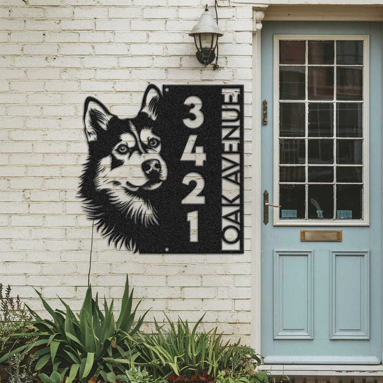Husky address sign mounted on a painted brick wall beside a wooden front door