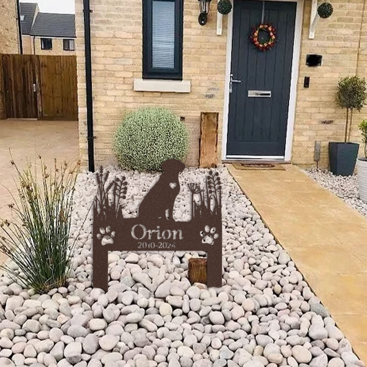 Labrador pet grave marker displayed among garden plants and stone edging, showing the heart-cutout silhouette design as an outdoor memorial accent.