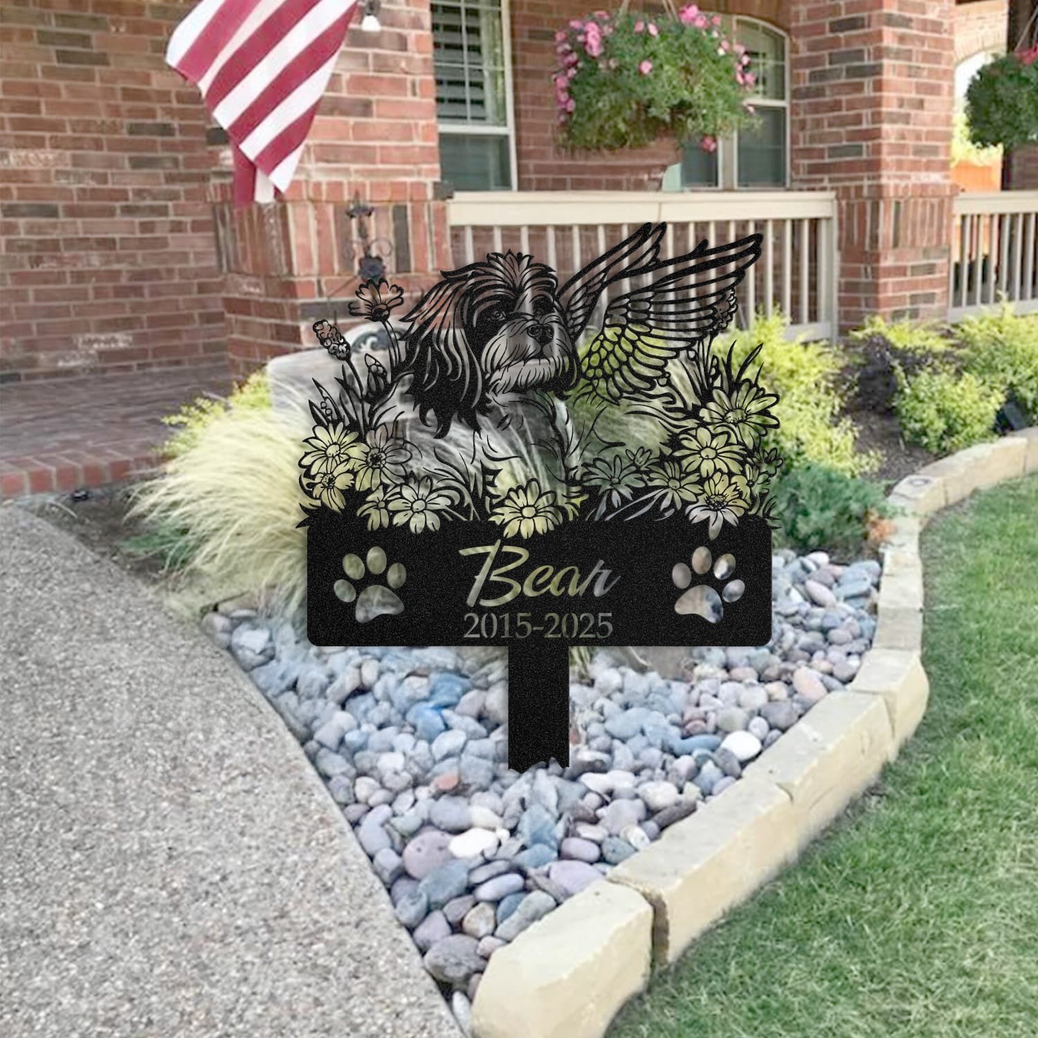 Lhasa Apso pet grave marker staged near a home entryway, showing the finished angel wings and daisy floral design and name plate outdoors.