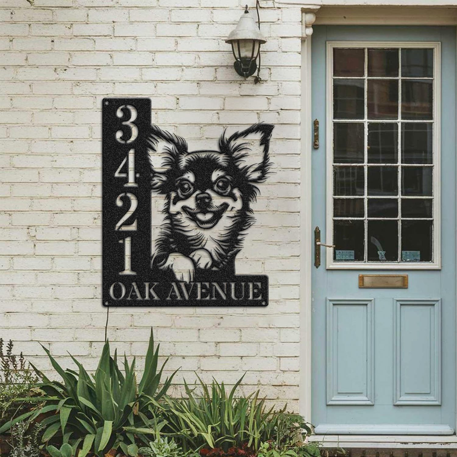 Longhair Chihuahua address sign mounted on a painted brick wall beside a wooden front door