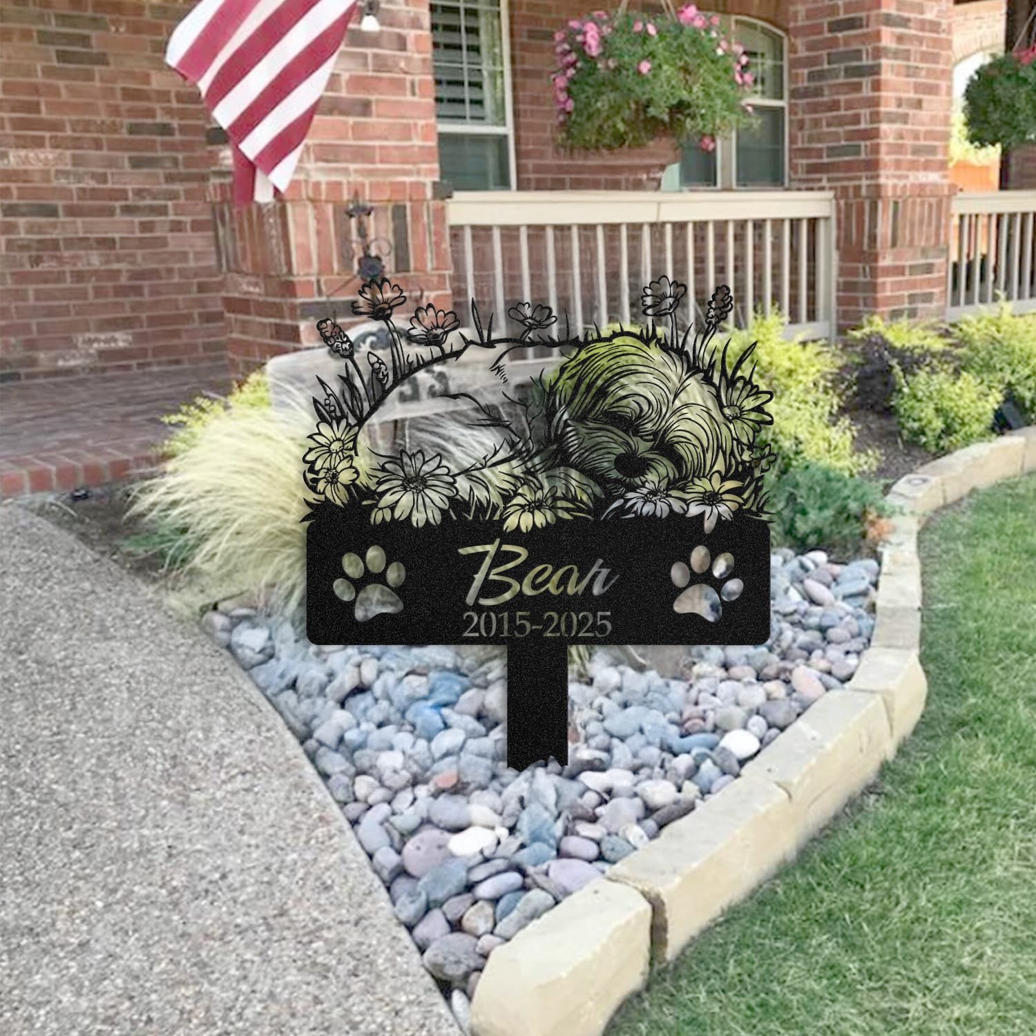 Maltese pet grave marker staged near a home entryway, showing the finished sleeping-pose daisy floral design and name plate outdoors.