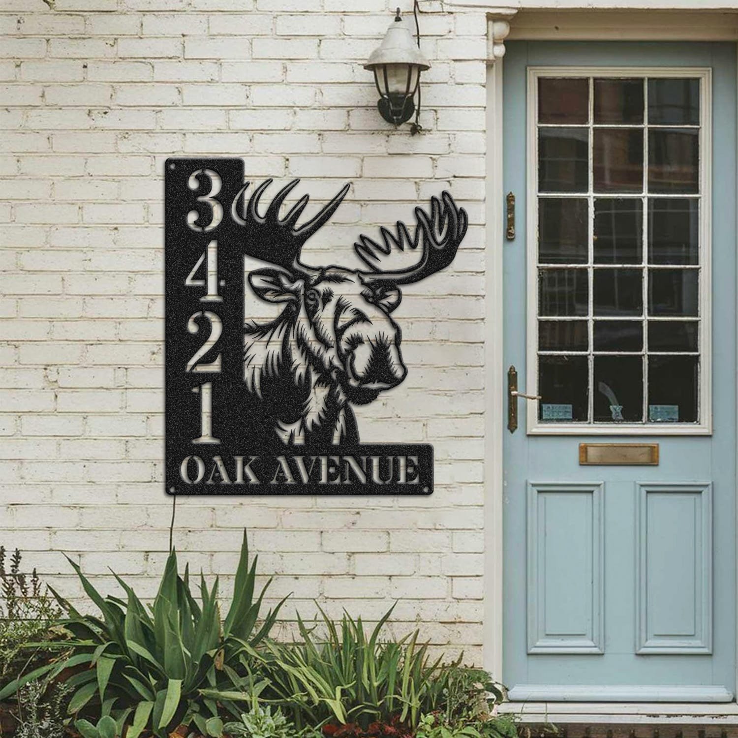 Moose address sign mounted on a painted brick wall beside a wooden front door