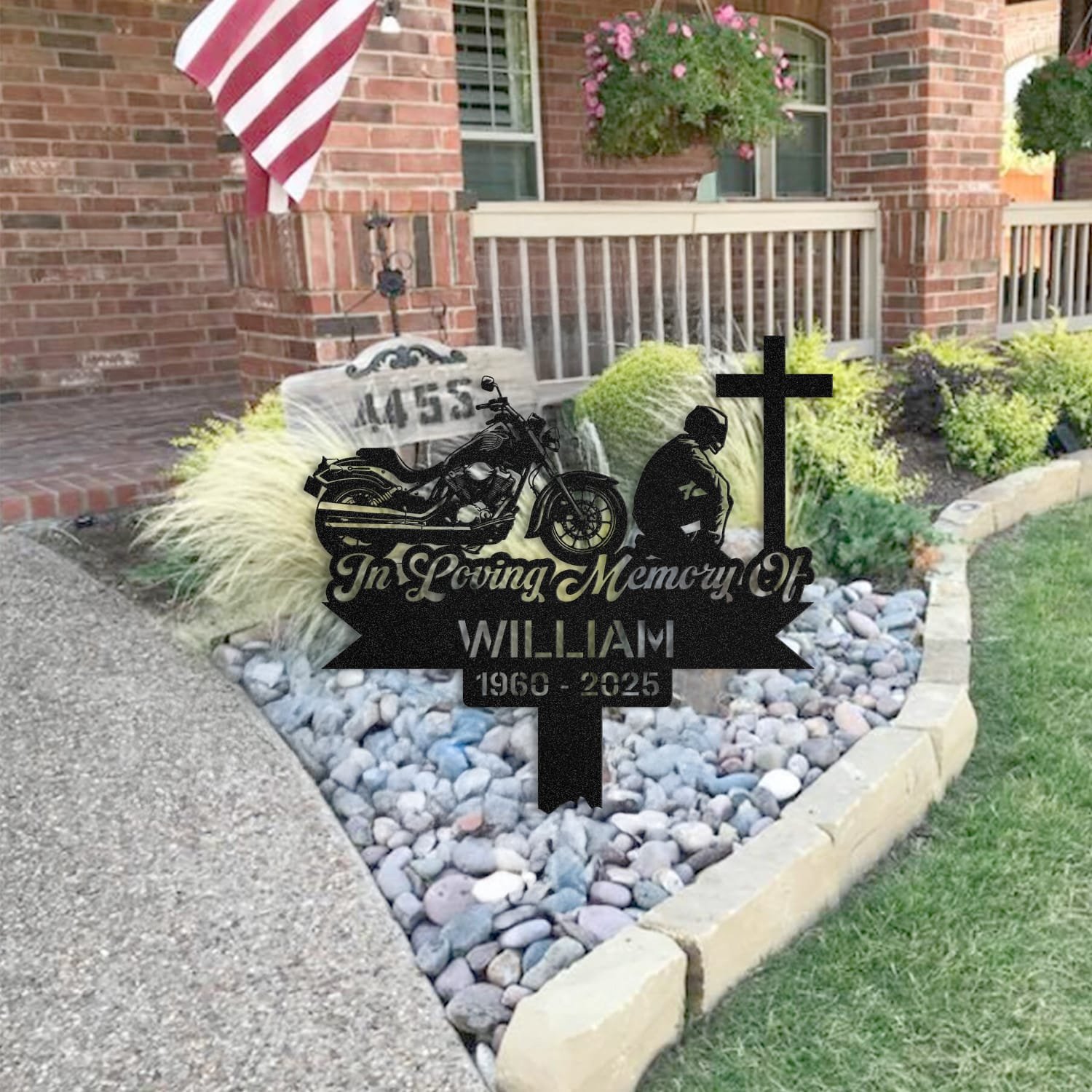 Motorcycle human grave marker staged near a home entryway, showing the finished motorcycle kneeling-at-the-cross design and name plate outdoors.