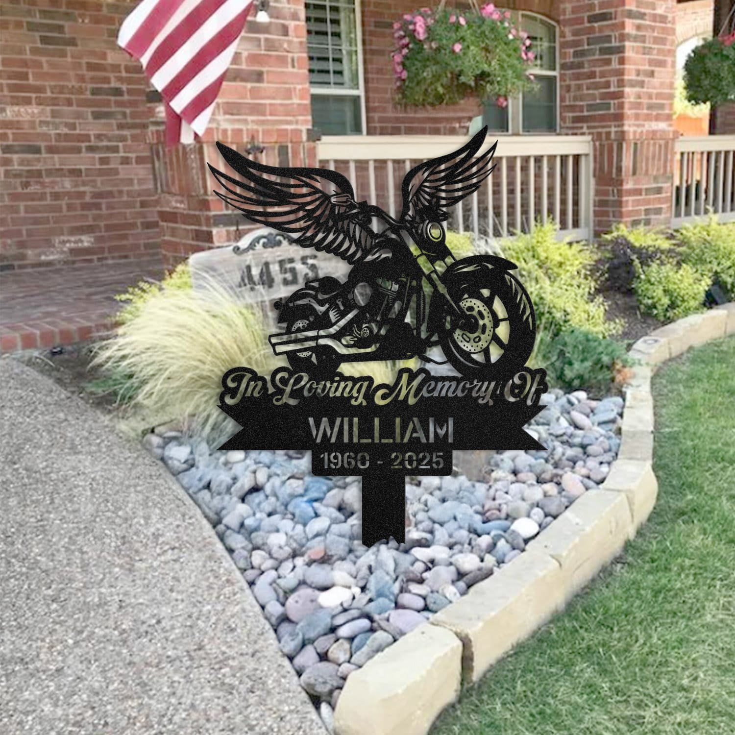 Motorcycle human grave marker staged near a home entryway, showing the finished motorcycle winged rider design and name plate outdoors.