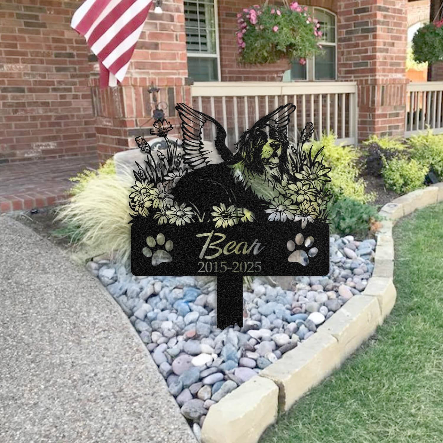 Newfoundland pet grave marker staged near a home entryway, showing the finished angel wings and daisy floral design and name plate outdoors.