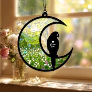 Crescent moon suncatcher with a perched Parrot silhouette over a stained-glass green lily of the valley field