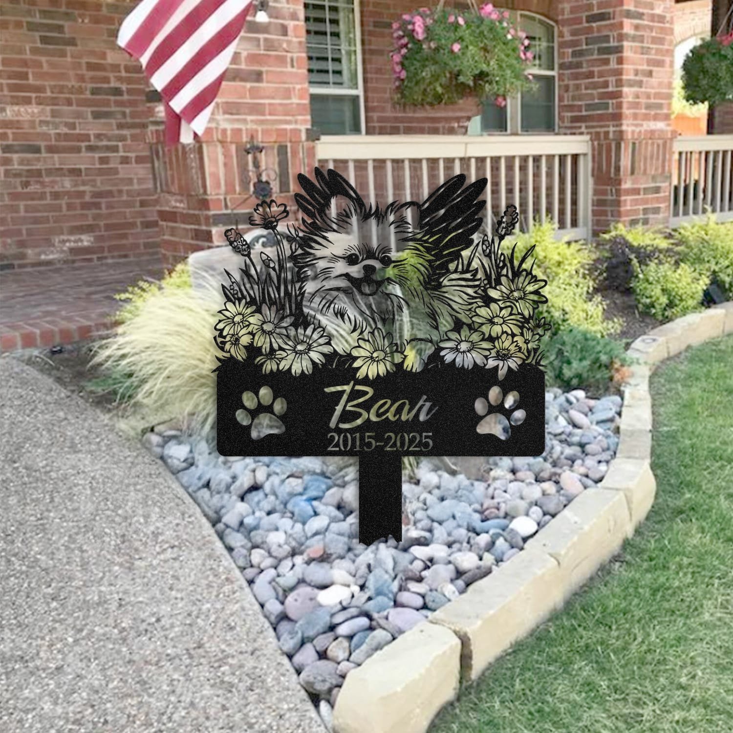 Pomeranian pet grave marker staged near a home entryway, showing the finished angel wings and daisy floral design and name plate outdoors.