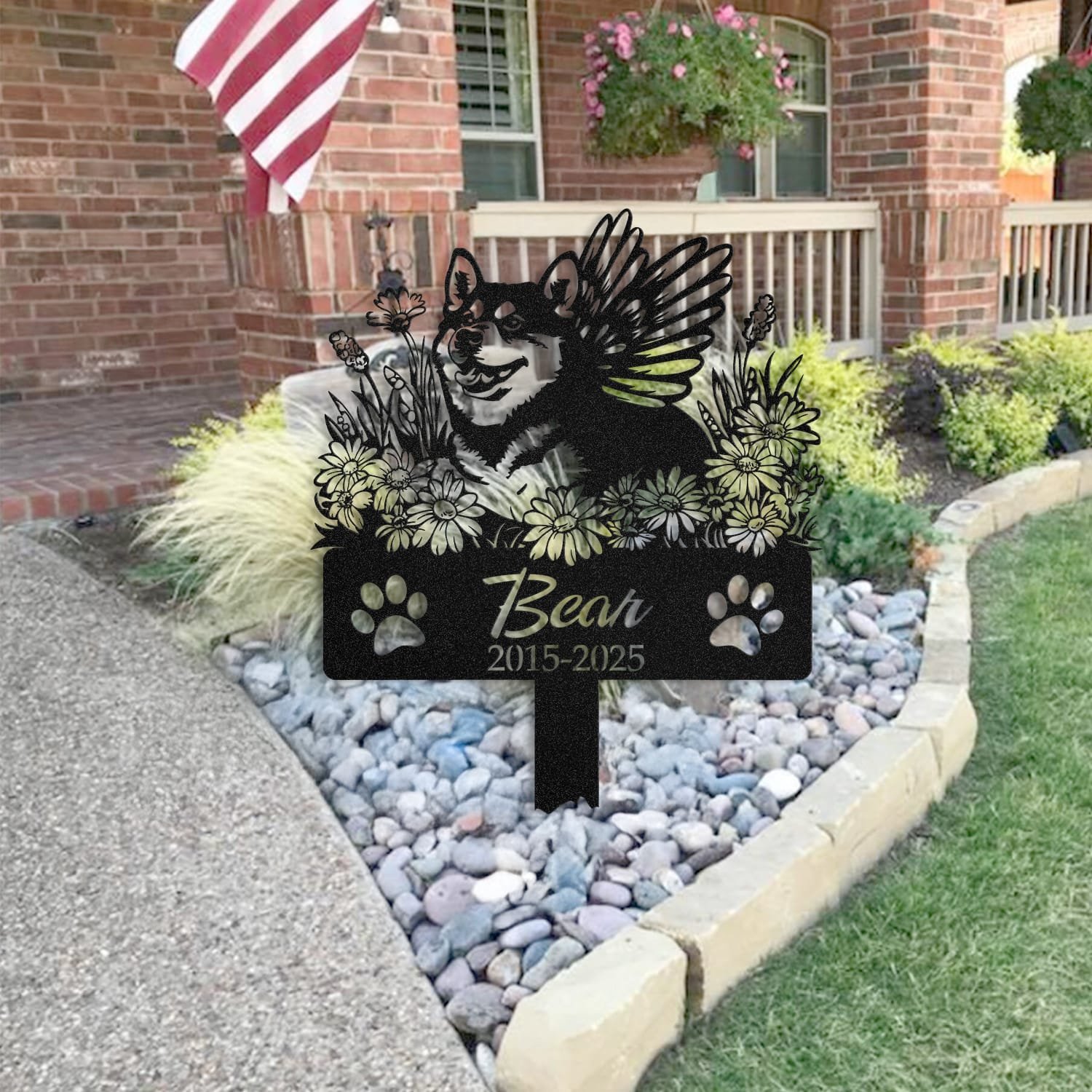 Shiba Inu pet grave marker staged near a home entryway, showing the finished angel wings and daisy floral design and name plate outdoors.