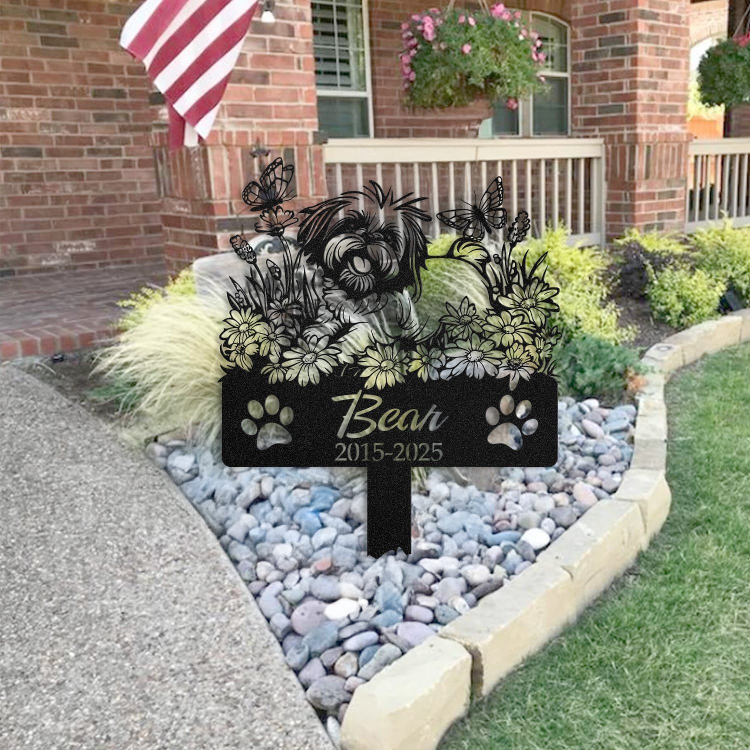 Shih Tzu pet grave marker staged near a home entryway, showing the finished daisy garden design with butterflies and name plate outdoors.